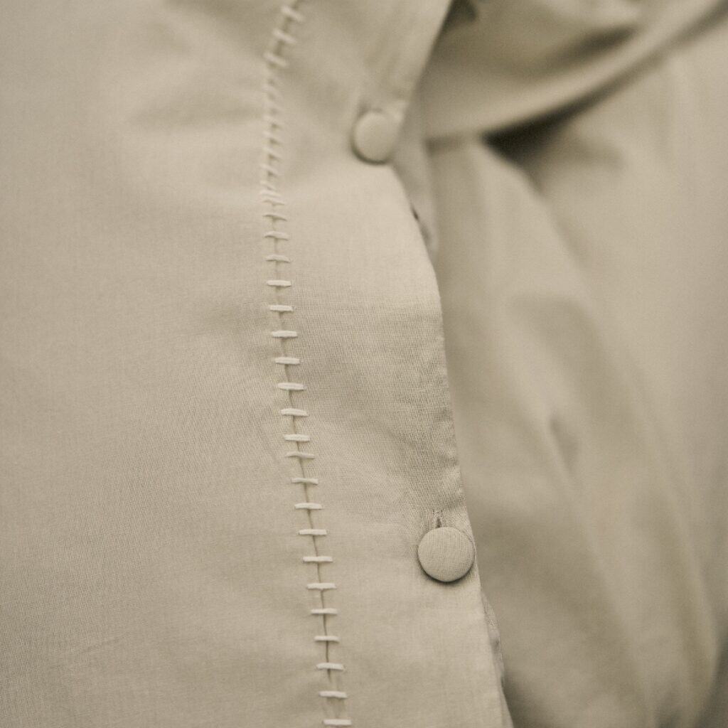 Närbild av påslakanset MARABEL i beige med tygknappar och broderad söm