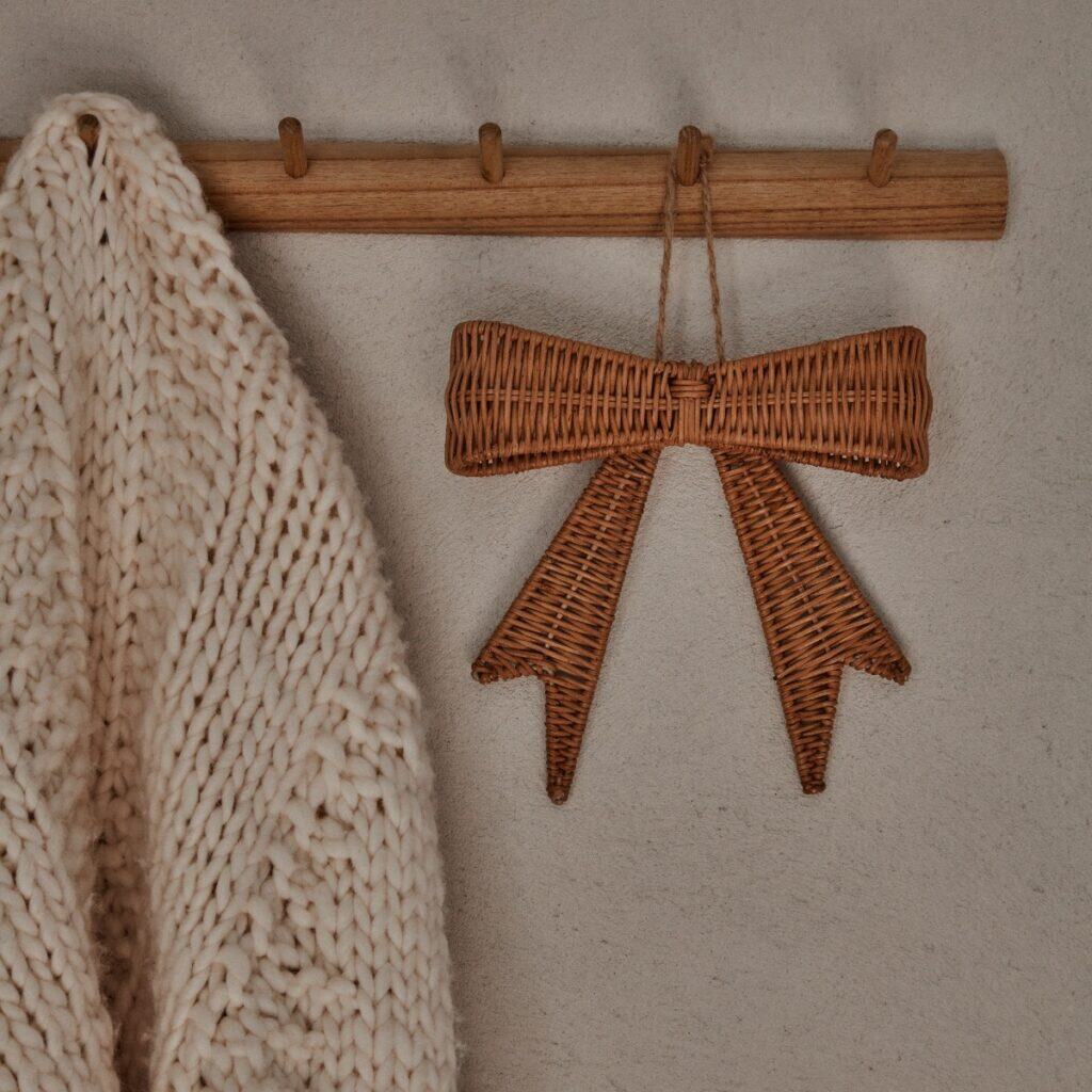 Rosett i rotting som hänger på träkrok bredvid stickad kofta
