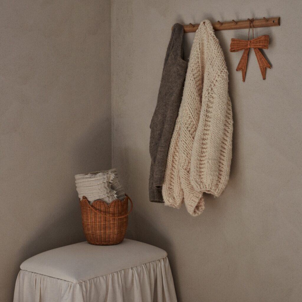 Rosett i rotting som dekoration på krok i hallen med stickade plagg