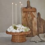 Rosett i rotting som dekoration på träbräda tillsammans med ljus och stilleben