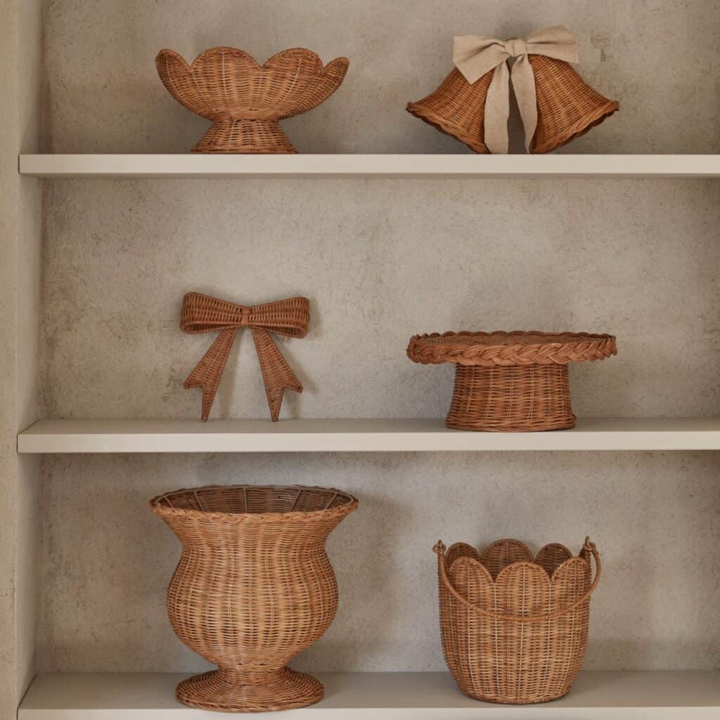 Rottingprodukter på hylla med fruktskål på fot, korgar och dekorativa detaljer i naturmaterial