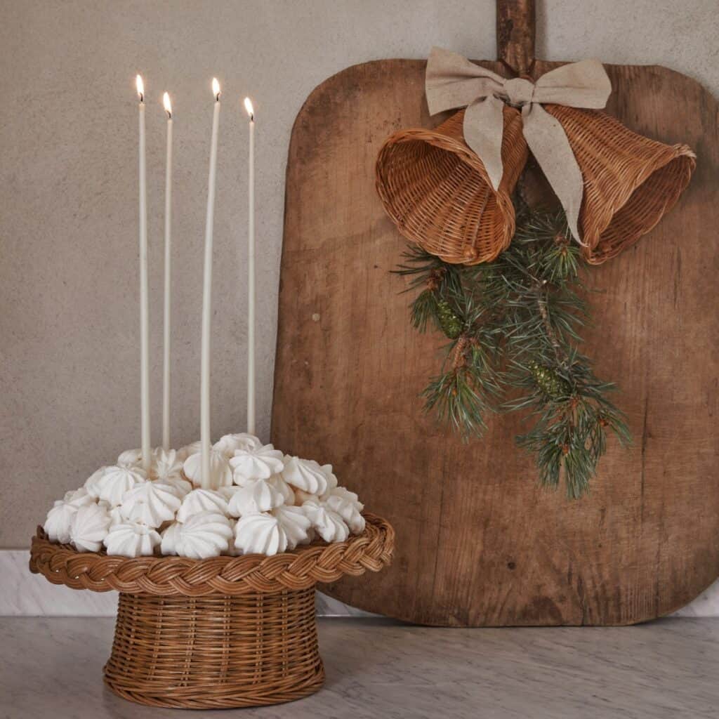 Rottingklockor med linneband som dekoration ovanför bord med ljusstake i rotting