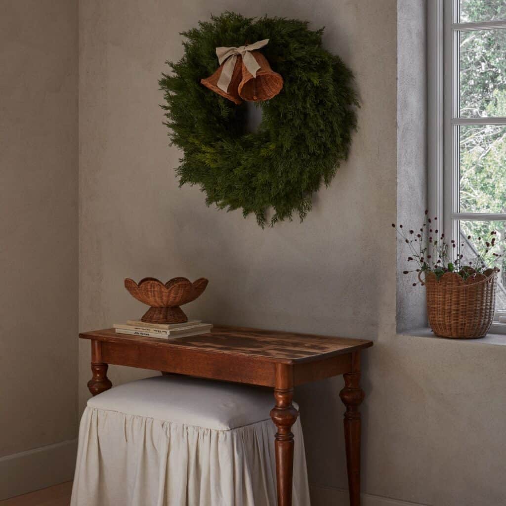 Rottingklockor med linneband på grön krans ovanför litet bord i naturmaterial