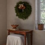 Rottingklockor med linneband på grön krans ovanför litet bord i naturmaterial