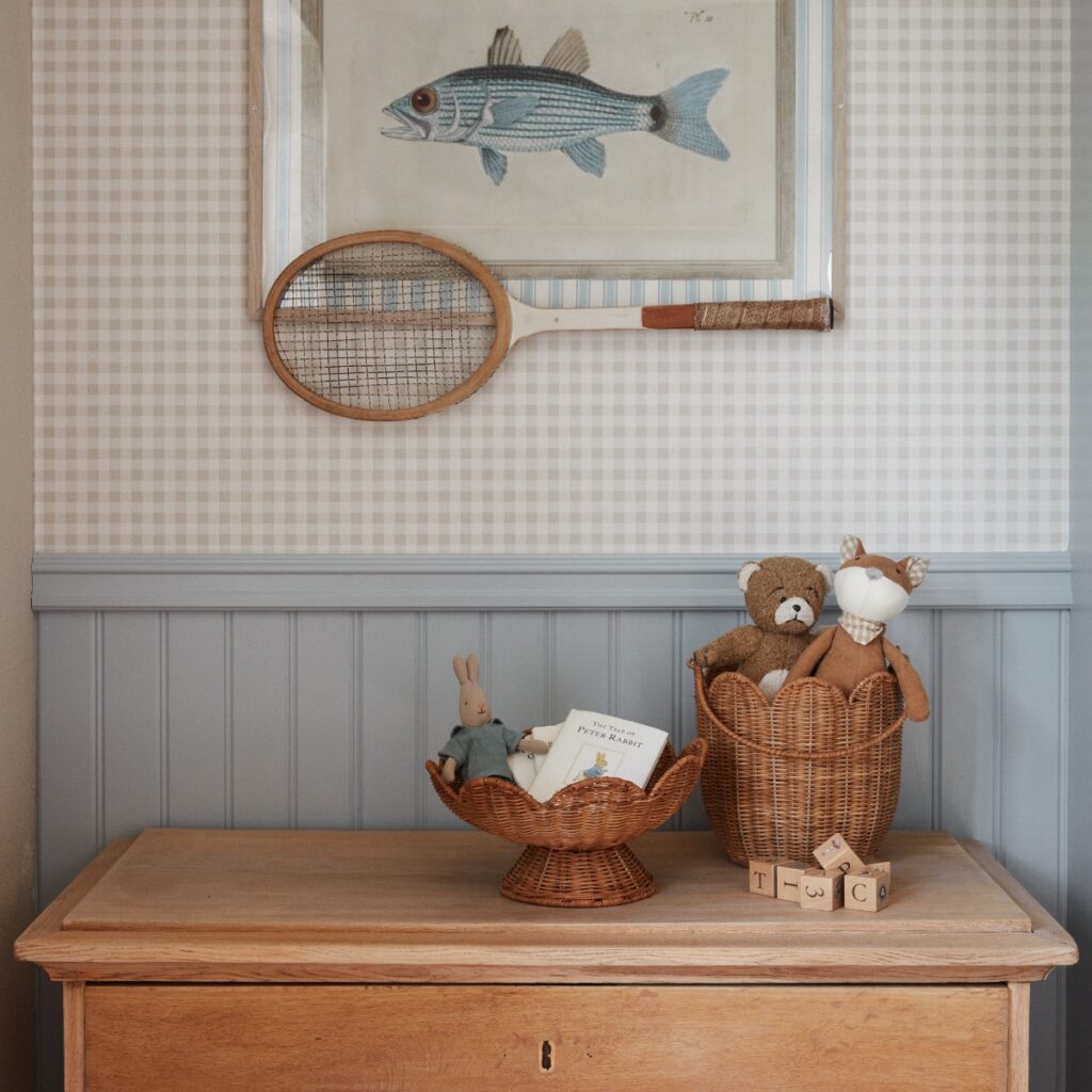 Handgjord korg i naturfärgad rotting använd för förvaring av leksaker på byrå i barnrum.