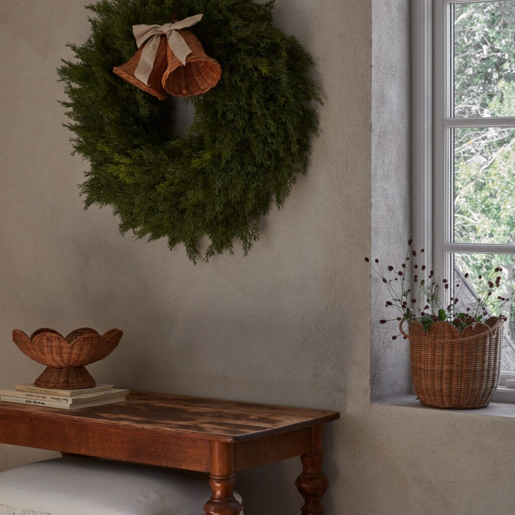 Handgjord korg i naturfärgad rotting med vågig kant placerad på fönsterbräda i lugn, tidlös inredningsmiljö.