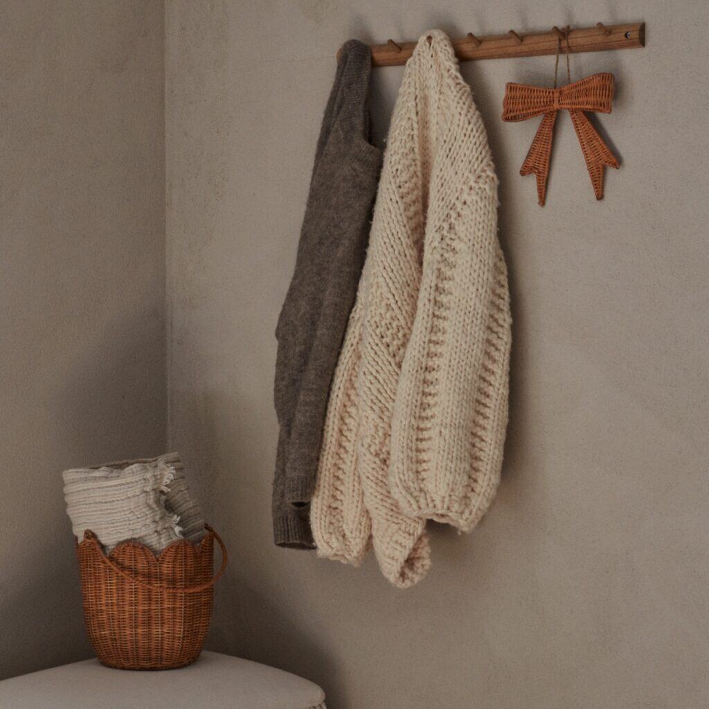 Handgjord korg i naturfärgad rotting med vågig kant använd som förvaring för plädar i lugn hallmiljö.