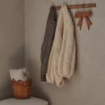 Handgjord korg i naturfärgad rotting med vågig kant använd som förvaring för plädar i lugn hallmiljö.