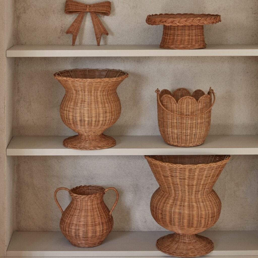 Handgjorda korgar och skålar i naturfärgad rotting uppställda på hylla i lugn, tidlös inredningsmiljö.
