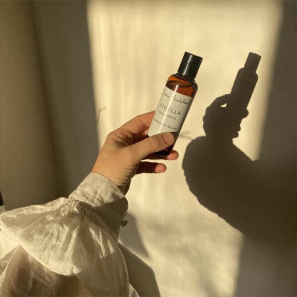 Kallpressad ekologisk Nigella sativa svartkumminolja i brun glasflaska.