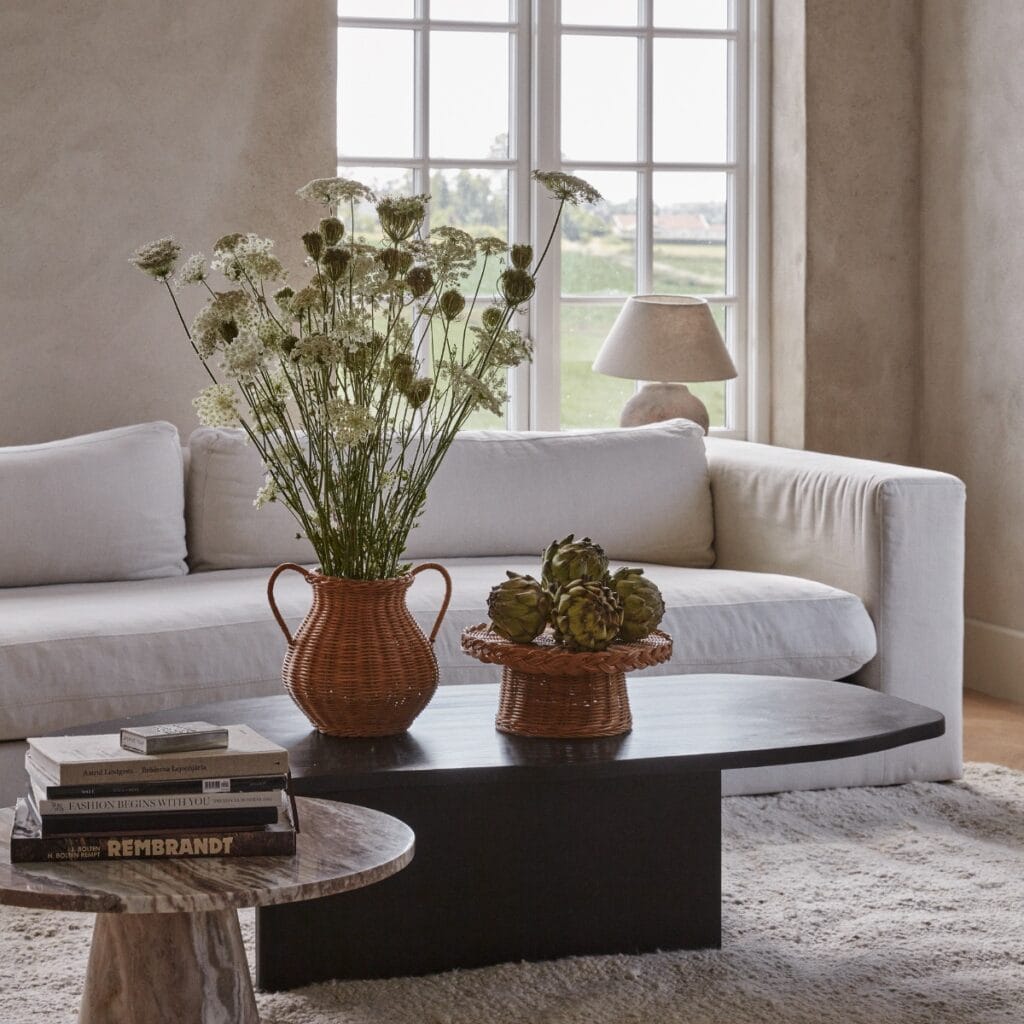 Vas i rotting med blommor placerad på soffbord i vardagsrum