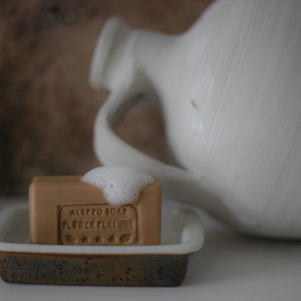 Aleppotvål med honung placerad i tvålkopp med skum på ytan