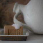 Aleppotvål med honung placerad i tvålkopp med skum på ytan