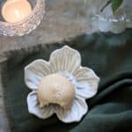 Detaljbild av dekorationsfat Ingrid i offwhite porslin med litet ljus på tyg