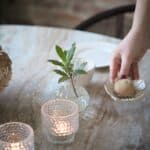 Dekorationsfat Ingrid i offwhite porslin med litet ljus, ställs på bord bredvid vas