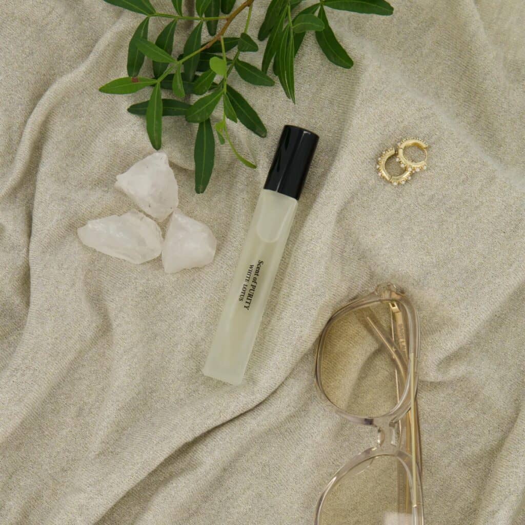 Eau de Parfum Scent of Purity från Washologi på ljust tyg med växt, glasögon och smycken