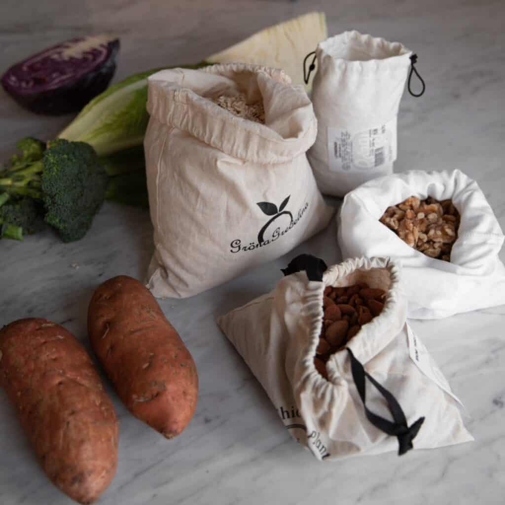 Liten ekologisk bomullspåse med dragsko fylld med nötter på köksbänk