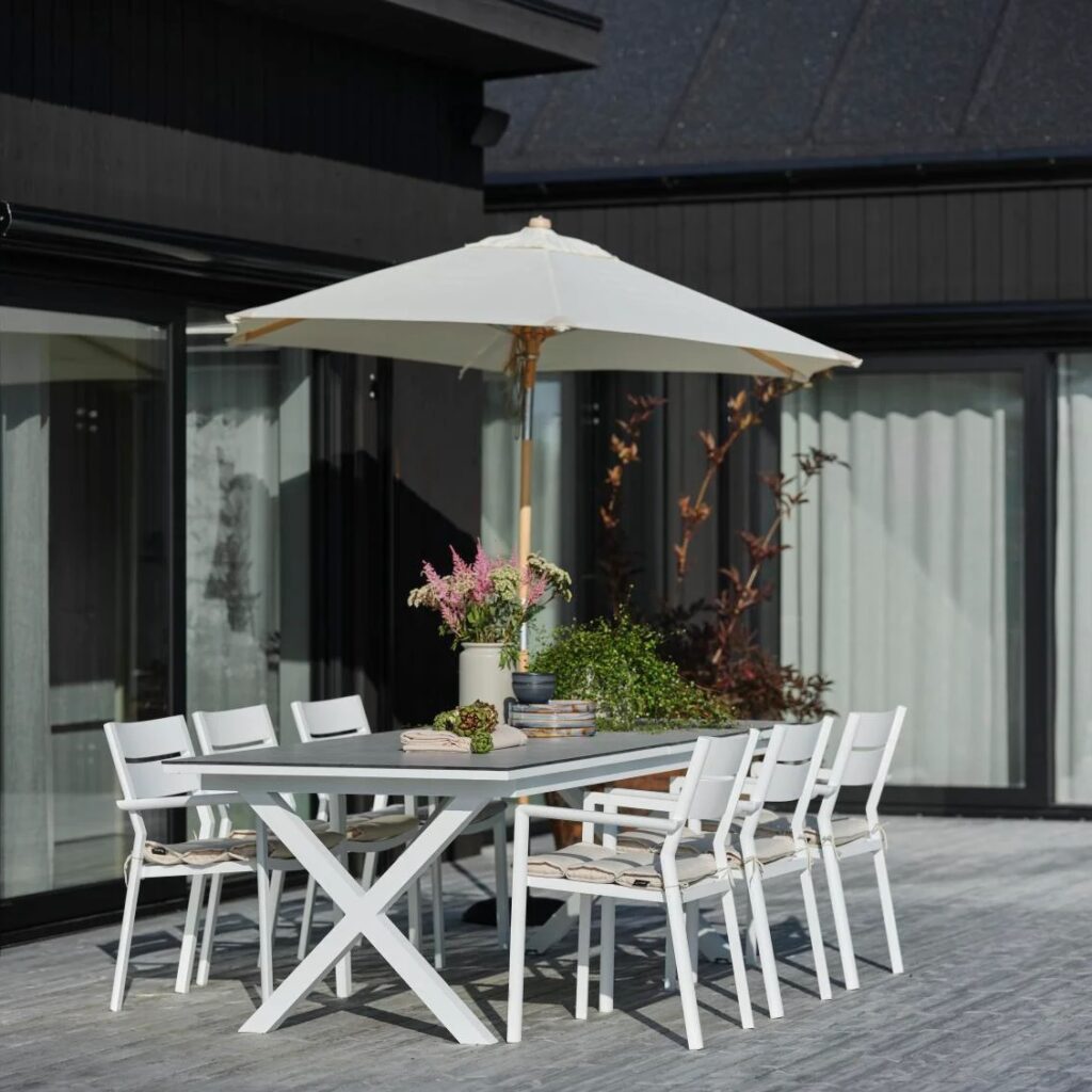 Parasoll i trä med off-white duk över matplats på uteplats