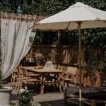 Parasoll i trä med off-white duk över matplats i grön trädgård