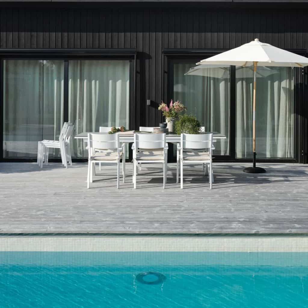 Parasoll i trä med off-white duk vid matplats på uteplats