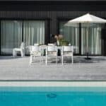 Parasoll i trä med off-white duk vid matplats på uteplats