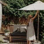 Parasoll i trä med off-white duk på grönskande uteplats