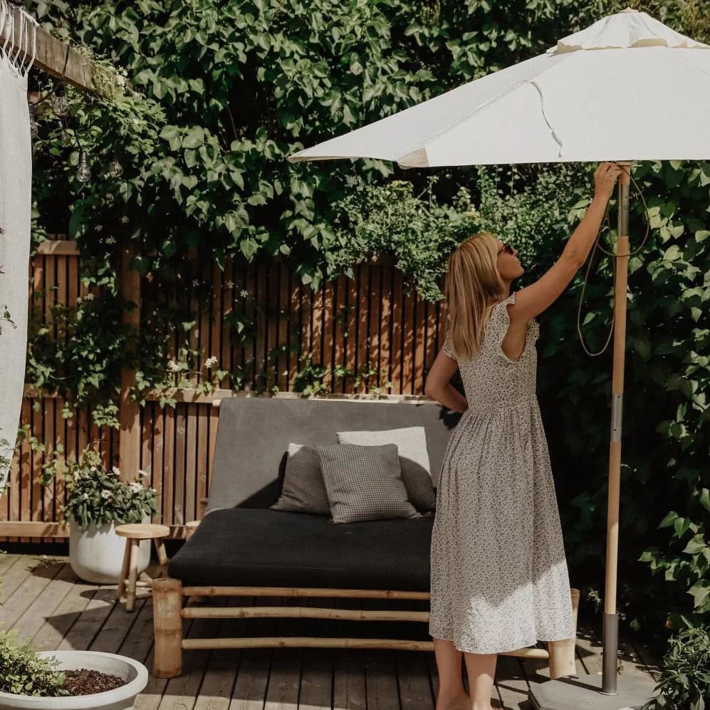 Parasoll i trä med off-white duk på grönskande uteplats