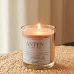 Doftljus i beige glas av sojavax med brinnande låga och varm träig doft