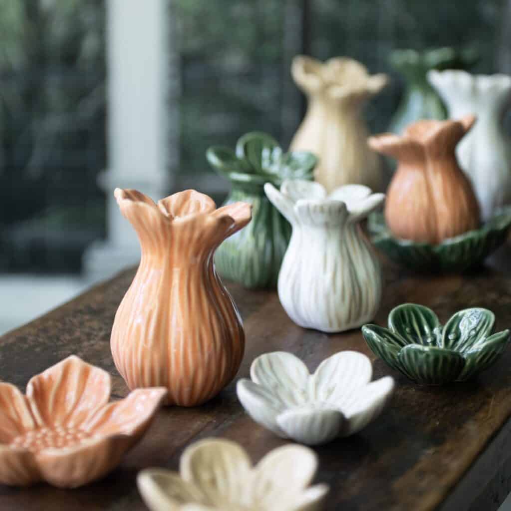 Persikorosa Ingrid vas i porslin på träbord tillsammans med vaser i flera färger