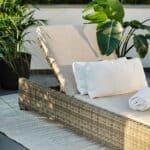 Ninja solsäng i rustik konstrotting med beige dyna på altan med gröna växter