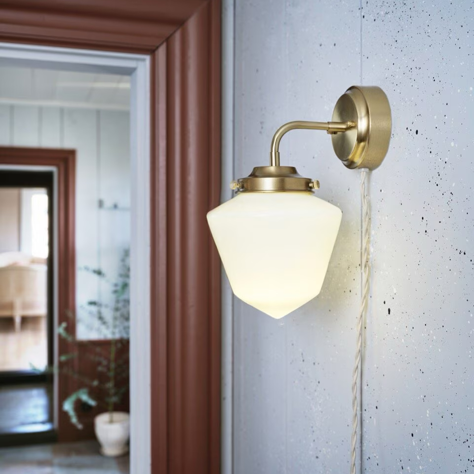 Tänd vägglampa Signe i mässing med vitt opalglas som sprider mjukt ljus