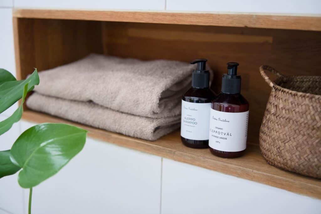 Vikta handdukar och badrumsprodukter på hylla under vårstädning