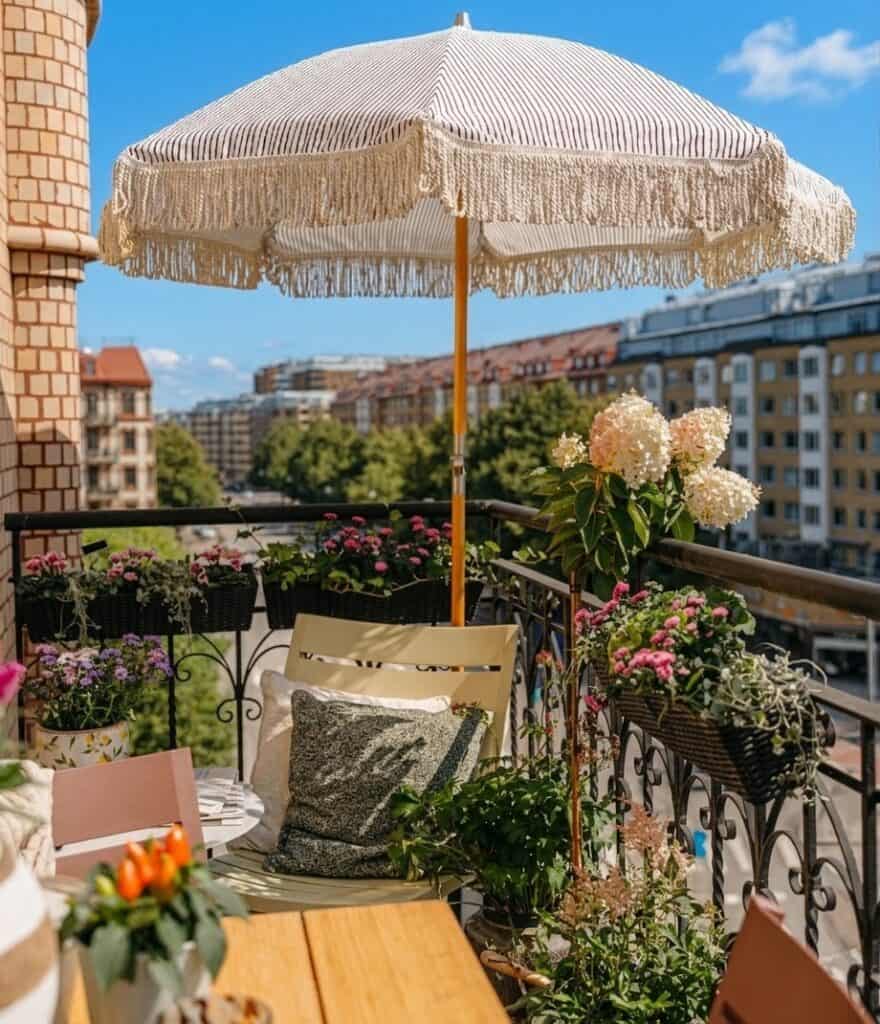 Mysig liten balkong med parasoll, växter och sittplats