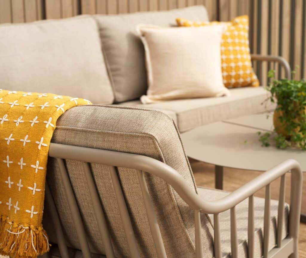 Dynor och filt på balkongmöbler som skapar en mysig och ombonad uteplats