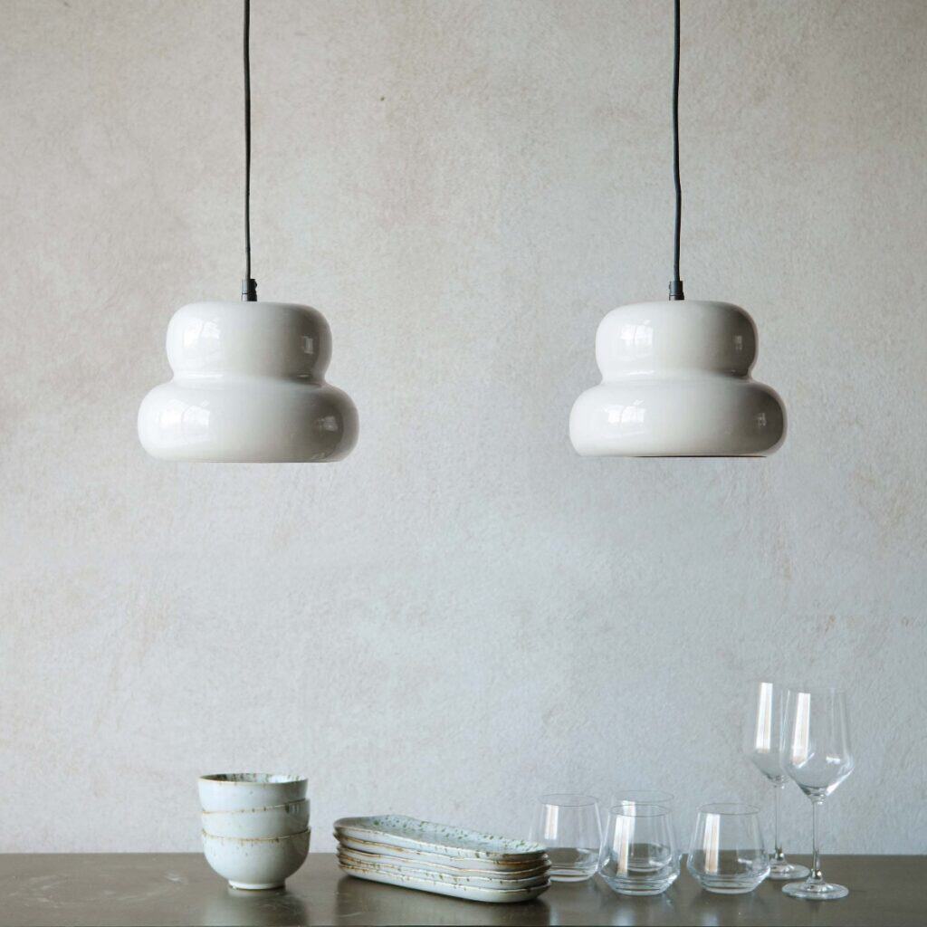 Två PADOVA taklampor i offwhite som hänger över ett matbord