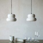 Två PADOVA taklampor i offwhite som hänger över ett matbord