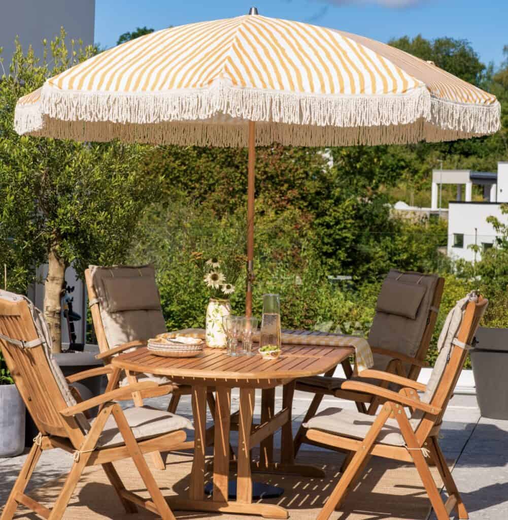 Parasoll på balkong som skapar skugga och en ombonad uteplats