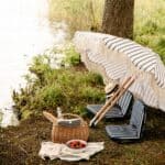 Picknickkorg Molly i pil under somrig picknick vid sjön med parasoll och sittdynor