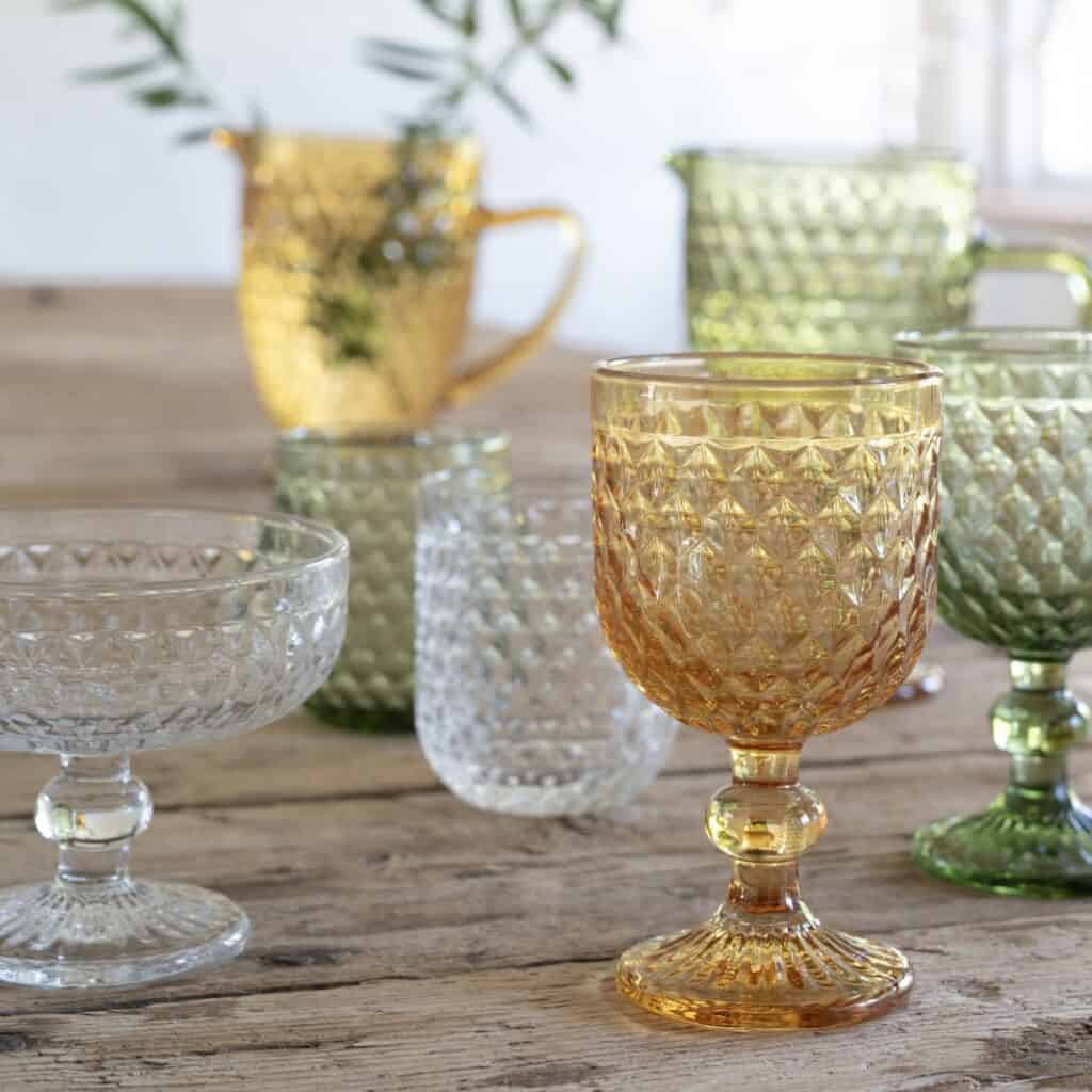 Coupéglas Elly i klart mönstrat glas tillsammans med färgade glas på dukat bord