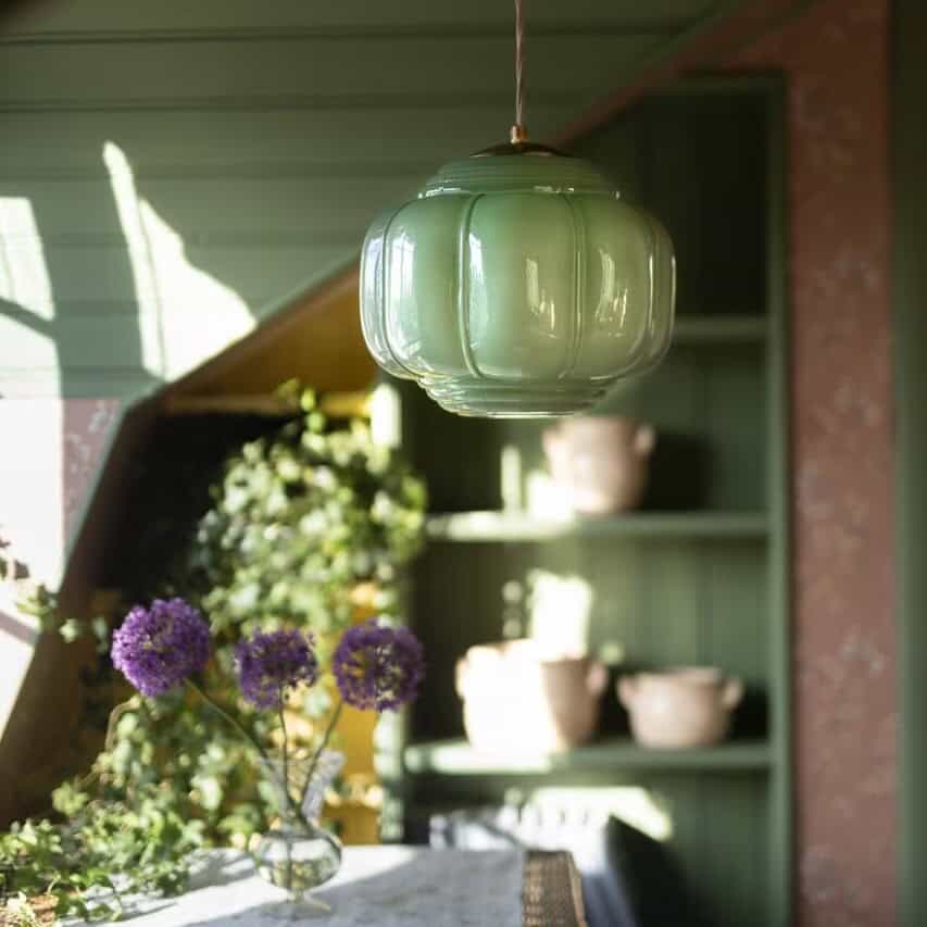 Taklampa Vincent i grönt opalglas över dukat bord i ombonad grön miljö, Ø27 cm.