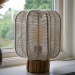 Bordslampa i offwhite bomullsrep med naturfärgad bas av sjögräs, placerad i ett fönster.