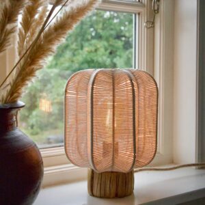 Tänd bordslampa i offwhite bomullsrep och sjögräs på fönsterbräda bredvid en vas med pampasgräs.