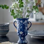 Amara blå vas i stengods med vita blommor och gröna kvistar på dukat bord
