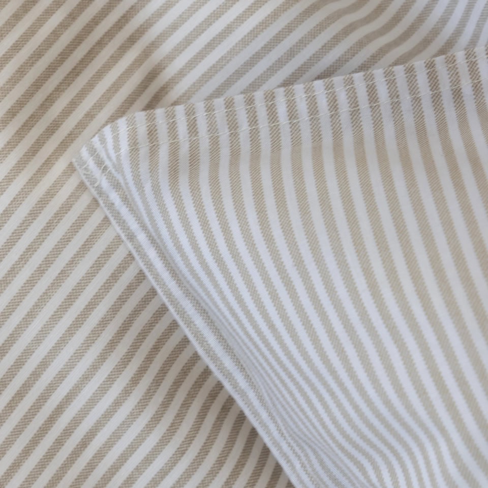 Närbild på Cille randigt påslakanset i beige och vit bomull